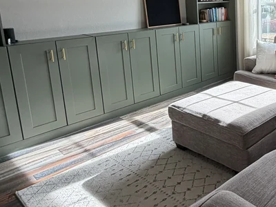 Paneled green built-in cabinet fronts with brass-tone pulls.